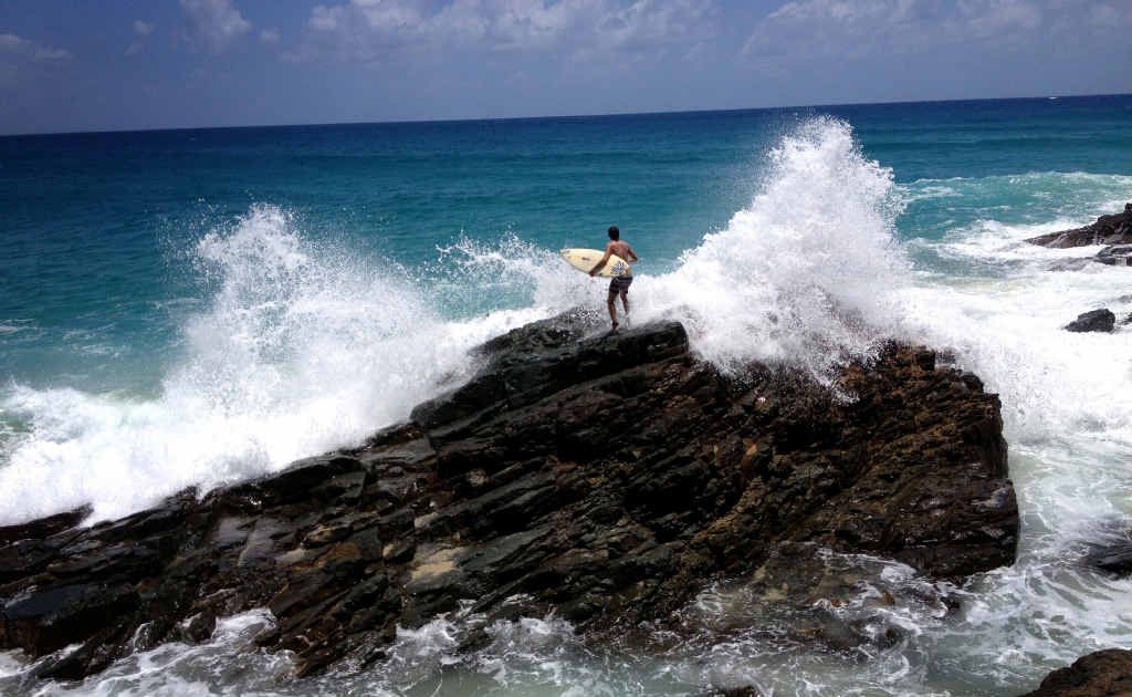 A surfer gets ready to jump of he rocks at Double Island Point. A surfer gets ready to jump of he rocks at Double Island Point.